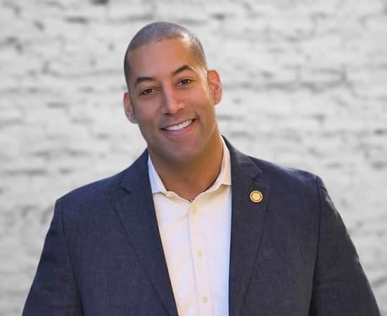 A photograph of Sean Spiller wearing a suit with a confident smile.