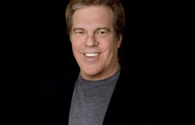 Jeff Margolis smiling in a black blazer and grey shirt, known for producing the Oscars and Emmy Awards