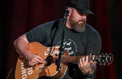 Scotty Hasting performing live on stage with a guitar during a country music event in Nashville